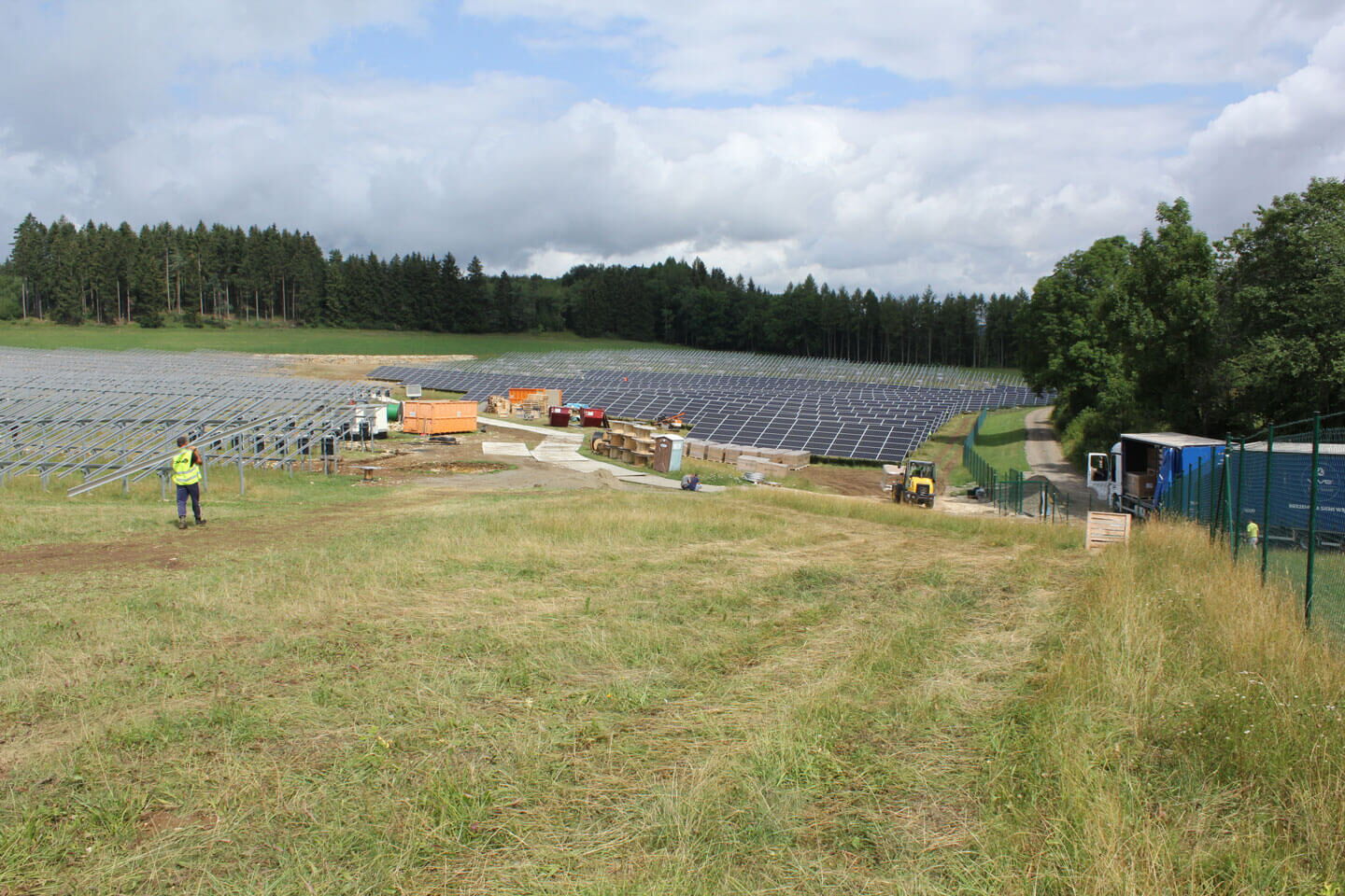 Aufbau einer Solaranlage auf einer Grünen Wiese am Waldrand