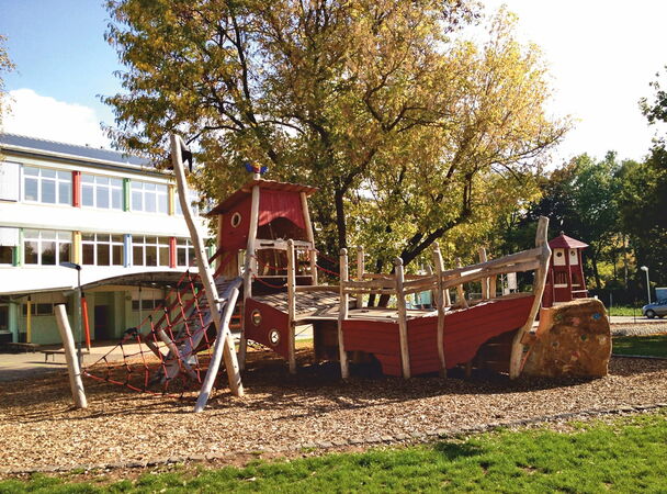 Holzspielschiff vor einer Schule